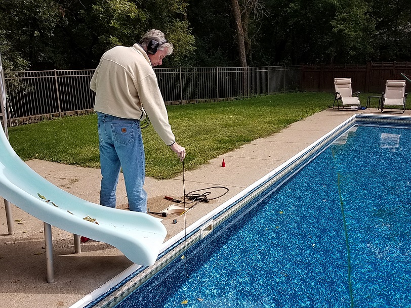 Leak technician using hydrophone to listen through pool wall